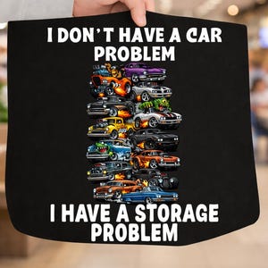 May include: Black tote bag with the text "I don't have a car problem, I have a storage problem." The bag features a colorful graphic of cartoon cars, including orange, purple, and blue vehicles.