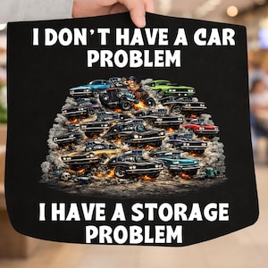 May include: Black tote bag with the text "I DON'T HAVE A CAR PROBLEM I HAVE A STORAGE PROBLEM." The bag features a graphic of many classic cars in various colours, including black, blue, green, and red.