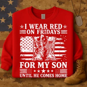 May include: Red sweatshirt with the text "I WEAR RED ON FRIDAYS FOR MY SON UNTIL HE COMES HOME." The design includes an American flag and combat boots. A tan boot is visible in the lower right corner.