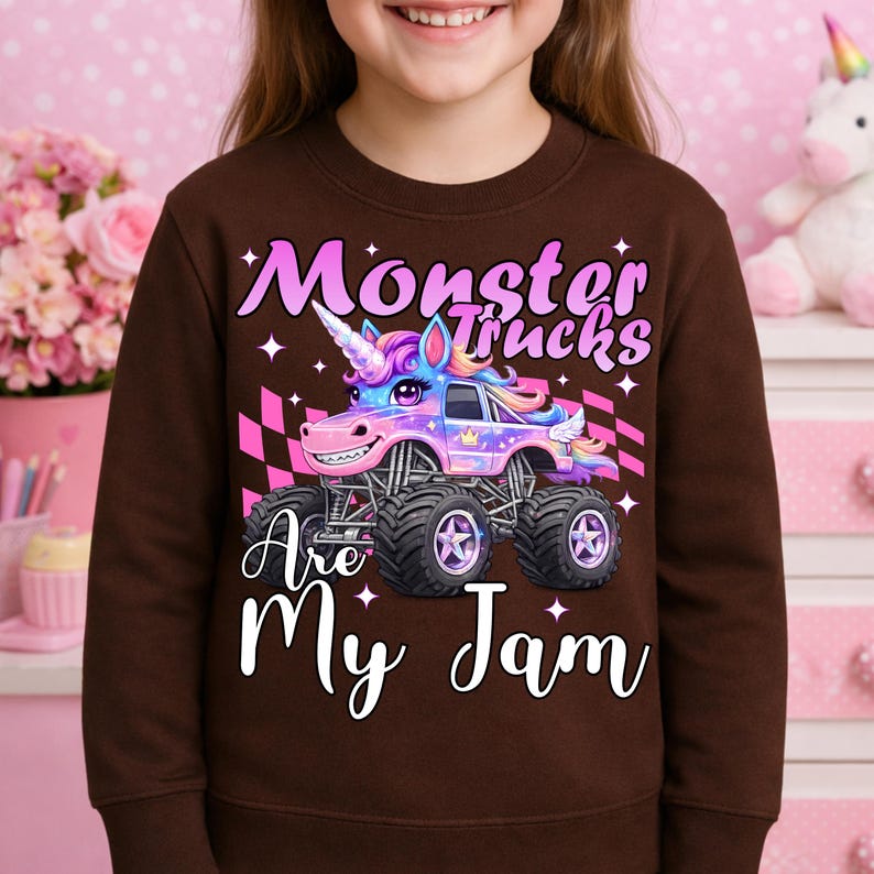 Puede incluir: Una sudadera marr&oacute;n con un gr&aacute;fico colorido de un cami&oacute;n monstruo dise&ntilde;ado como un unicornio. El texto "Monster Trucks Are My Jam" se muestra en escritura blanca. El cami&oacute;n monstruo tiene neum&aacute;ticos negros grandes y una carrocer&iacute;a rosa y morada.