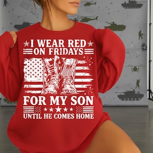 May include: A red sweatshirt with the text "I WEAR RED ON FRIDAYS FOR MY SON UNTIL HE COMES HOME" in white. The design includes an American flag and military boots.