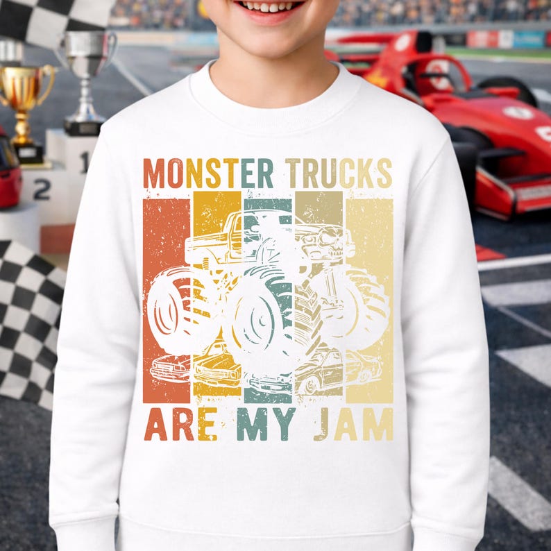 Puede incluir: Sudadera blanca con un gr&aacute;fico retro de monster truck. El dise&ntilde;o presenta una ilustraci&oacute;n de monster truck con el texto "MONSTER TRUCKS ARE MY JAM". El gr&aacute;fico utiliza acentos de color naranja, amarillo y turquesa en un estilo vintage.