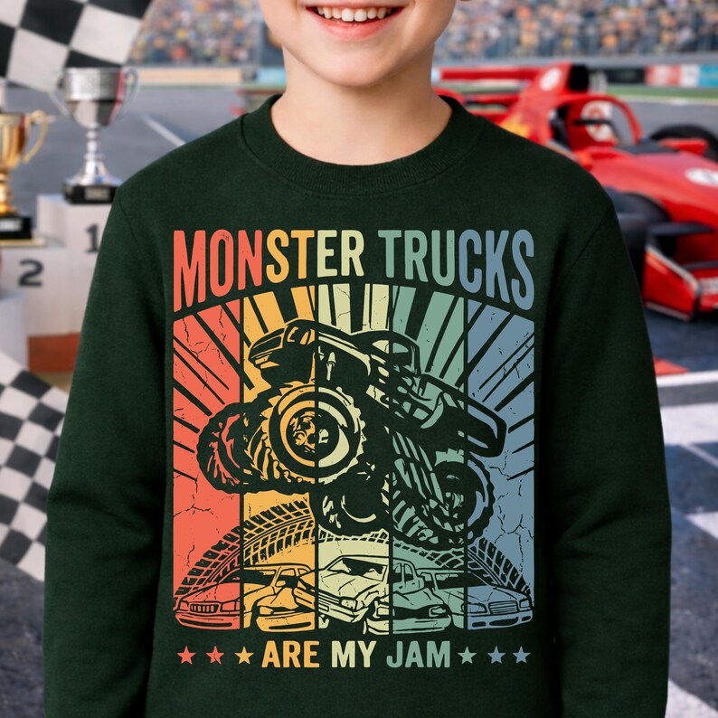 May include: Dark green sweatshirt with a colorful graphic that says "MONSTER TRUCKS ARE MY JAM." The graphic features a monster truck, tire tracks, and several cars in a retro style.