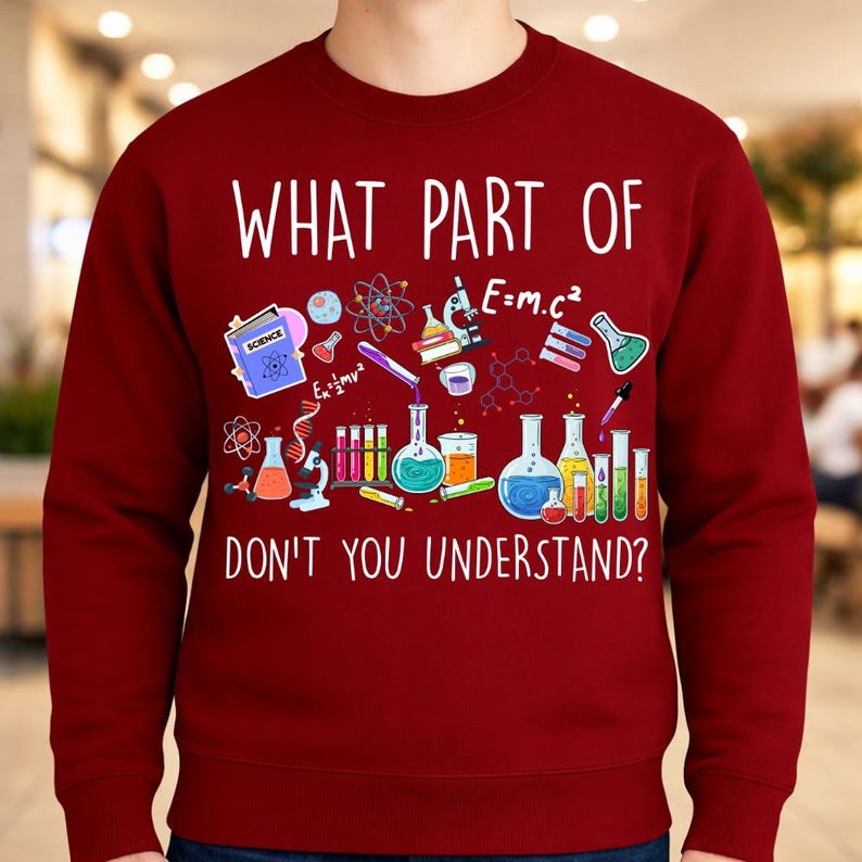 Może przedstawiać: Bordowa bluza z napisem "WHAT PART OF DON'T YOU UNDERSTAND?" w kolorze białym. Projekt zawiera kolorowe ilustracje element&oacute;w związanych z nauką, takich jak zlewki, prob&oacute;wki i symbole naukowe.