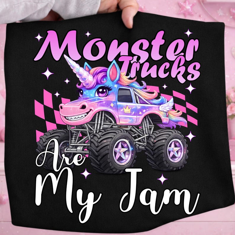 Puede incluir: Tela negra con un gr&aacute;fico colorido de un monster truck dise&ntilde;ado como un unicornio. El texto dice "Monster Trucks Are My Jam" en blanco y rosa. El cami&oacute;n tiene ruedas grandes y una cara sonriente.
