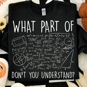 Peut inclure: Sweat-shirt noir avec texte blanc et &eacute;quations math&eacute;matiques. Le texte dit "WHAT PART OF DON'T YOU UNDERSTAND ?" Le design comprend des formes g&eacute;om&eacute;triques et des formules. Id&eacute;al pour les amateurs de math&eacute;matiques.