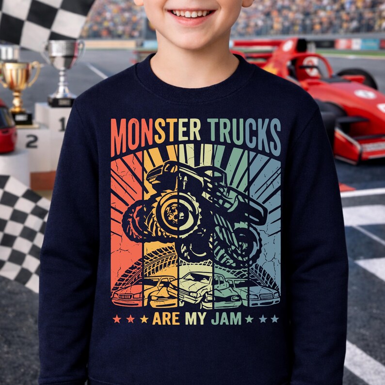 May include: Navy blue sweatshirt with a colorful graphic featuring a monster truck, the text "MONSTER TRUCKS" and "ARE MY JAM". The design includes a retro sunset and several cars.