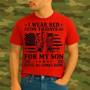 May include: Red t-shirt with the text "I WEAR RED ON FRIDAYS FOR MY SON UNTIL HE COMES HOME" and an American flag design with military boots. The shirt is worn by a person.