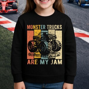 Puede incluir: Sudadera negra con un gr&aacute;fico colorido de un monster truck y el texto "MONSTER TRUCKS ARE MY JAM". El dise&ntilde;o presenta un estilo vintage con una ilustraci&oacute;n de monster truck y una paleta de colores retro.