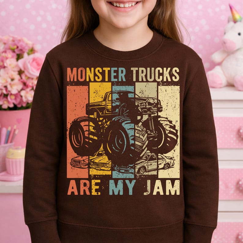 Puede incluir: Una sudadera marr&oacute;n con un gr&aacute;fico de monster truck y el texto "MONSTER TRUCKS ARE MY JAM". El dise&ntilde;o incluye una ilustraci&oacute;n de monster truck en negro, azul, amarillo, naranja y beige.
