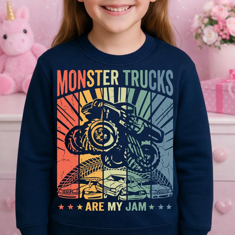 May include: Navy blue sweatshirt with a colorful graphic that says "MONSTER TRUCKS ARE MY JAM." The design features a monster truck, tire tracks, and several cars in a retro style.