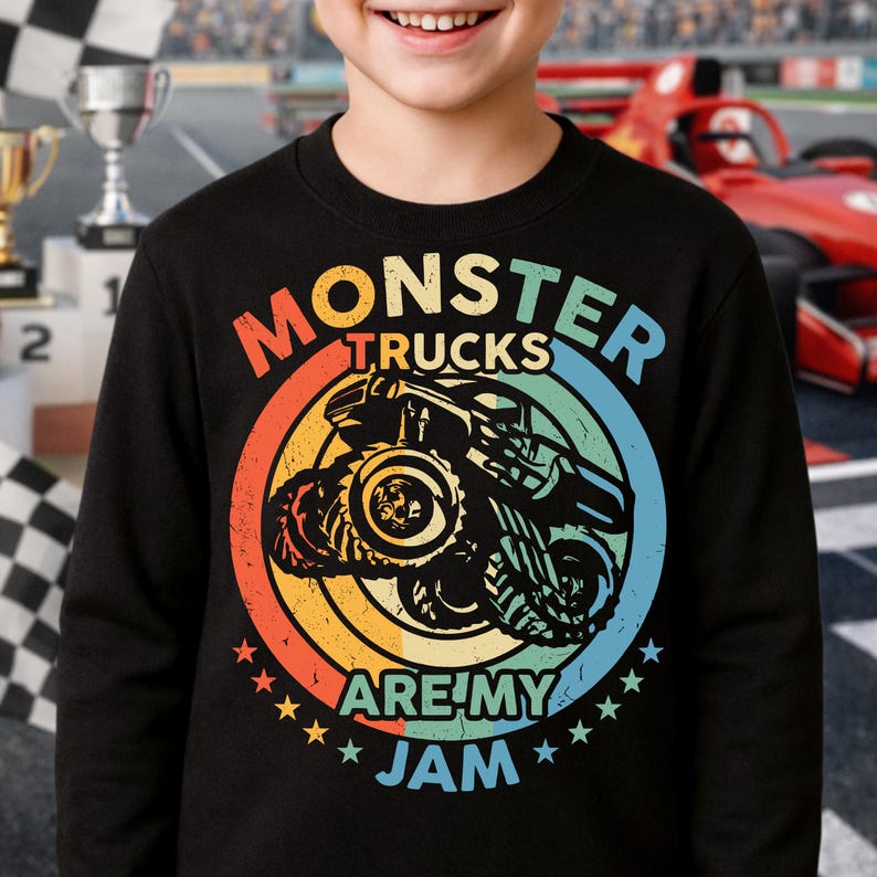 May include: Black sweatshirt with a colorful graphic of a monster truck inside a circle with the text "MONSTER TRUCKS ARE MY JAM". The design features orange, yellow, blue, and green colors, with star accents.