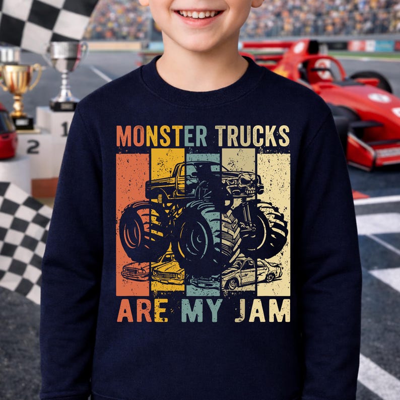 Puede incluir: Sudadera azul marino con un dise&ntilde;o retro que presenta un gr&aacute;fico de monster truck y el texto "MONSTER TRUCKS ARE MY JAM". El dise&ntilde;o incorpora rayas verticales naranjas, amarillas y azules.