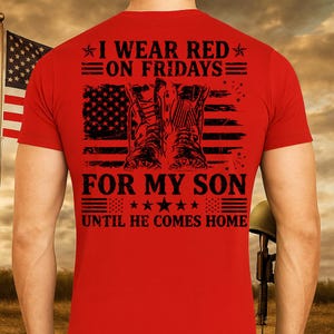 May include: Red t-shirt with a graphic featuring military boots, an American flag, and the text "I WEAR RED ON FRIDAYS FOR MY SON UNTIL HE COMES HOME". The design is in black and white.