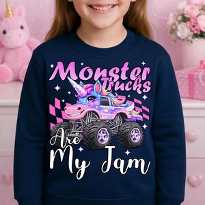 Puede incluir: Sudadera azul marino con un dise&ntilde;o de cami&oacute;n monstruo colorido con un cuerno y alas de unicornio. El texto "Monster Trucks Are My Jam" est&aacute; escrito en blanco. El dise&ntilde;o incluye estrellas y una bandera a cuadros.