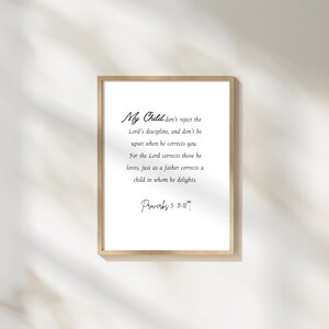 May include: A framed print with the text "My Child" and a quote from Proverbs 3:11-12. The text is in a handwritten style font on a white background, framed by a light wood frame.