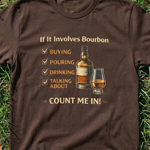 Può includere: T-shirt marrone con la scritta "If It Involves Bourbon" e una grafica di una bottiglia e un bicchiere di bourbon. Il testo include un elenco di attività relative al bourbon: comprare, versare, bere e parlare. È inclusa anche la frase "Count Me In!".