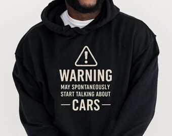 May include: Black hoodie with the text "WARNING MAY SPONTANEOUSLY START TALKING ABOUT - CARS -" in white. The warning symbol is a white triangle with an exclamation point.