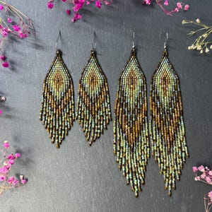 May include: Two pairs of dangle earrings crafted from small glass beads in shades of green, brown, and metallic bronze. The earrings feature a pointed top section and a long, fringed bottom edge, suspended from silver-toned metal ear wires.
