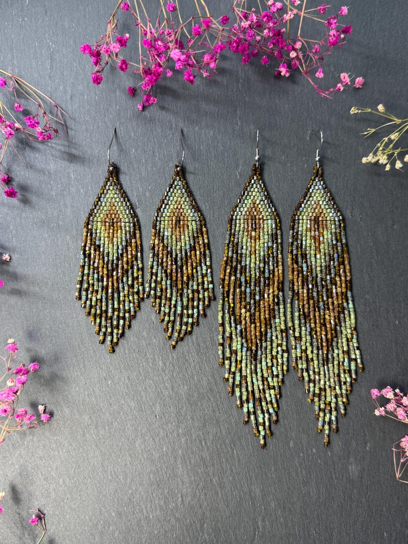 May include: Two pairs of dangle earrings crafted from small glass beads in shades of green, brown, and metallic bronze. The earrings feature a pointed top section and a long, fringed bottom edge, suspended from silver-toned metal ear wires.
