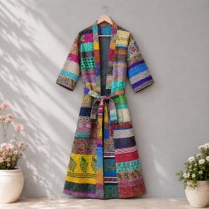May include: A long-length robe featuring a patchwork design composed of various colorful fabric panels. The garment includes three-quarter length sleeves, a matching tie belt at the waist, and a vibrant mix of floral, geometric, and peacock patterns.
