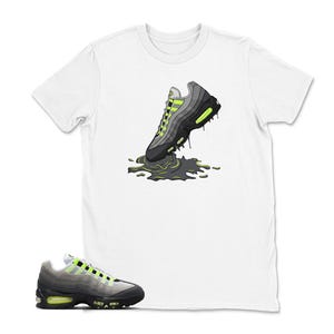 Może przedstawiać: Biała koszulka z grafiką szaro-czarnego buta sportowego z neonowo-zielonymi akcentami, kt&oacute;ry wydaje się topić w ciemnozielonej kałuży. Projekt jest stylizowaną ilustracją. Poniżej pokazano pasujący but sportowy.