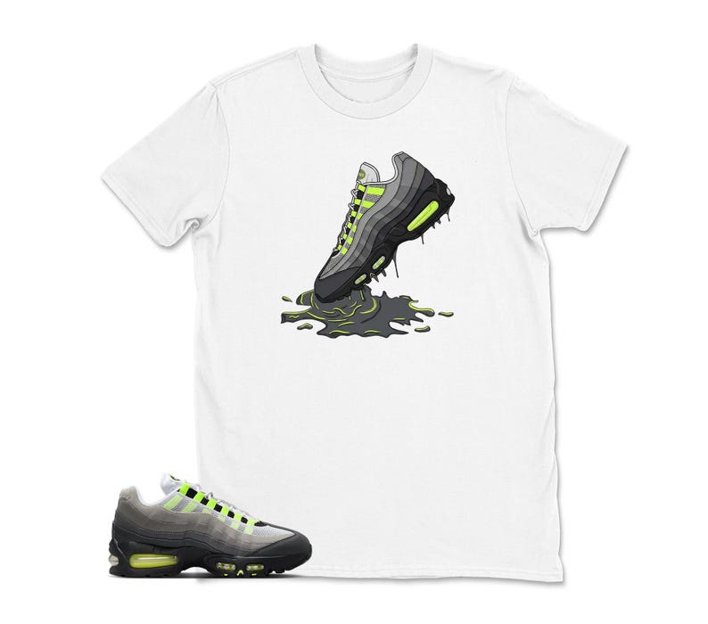 Może przedstawiać: Biała koszulka z grafiką szaro-czarnego buta sportowego z neonowo-zielonymi akcentami, kt&oacute;ry wydaje się topić w ciemnozielonej kałuży. Projekt jest stylizowaną ilustracją. Poniżej pokazano pasujący but sportowy.