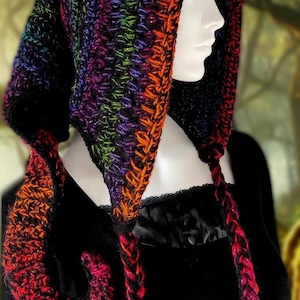 May include: A colorful, hooded crochet cowl in a rainbow of colors, including red, orange, green, purple, and black. The cowl has long, braided ties and the text "Whimsy Darkly Créations" at the bottom.