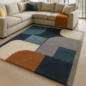 Puede incluir: Una alfombra moderna con un diseño geométrico en tonos azul marino, turquesa, gris, beige y óxido. La alfombra está colocada sobre un suelo de madera clara, con un sofá seccional beige en el fondo. El diseño incluye formas curvas y lineales.