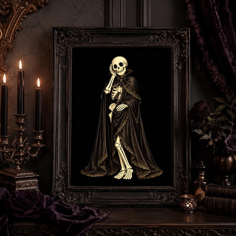 May include: A framed wall art print featuring a cream-coloured skeleton wearing a long, flowing black cape with intricate lace trim. The skeleton is depicted in a standing pose with one hand resting near its face, set against a solid black background.