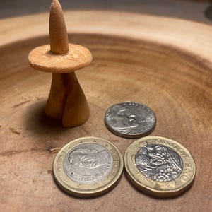 Könnte beinhalten: Eine weiße Keramik-Tasse mit schwarzem Henkel und dem Text "But First, Coffee" in schwarzer, fetter Schrift. Die Tasse steht auf einer weißen Oberfläche.