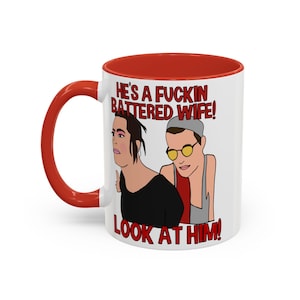 Könnte beinhalten: Weiße Keramiktasse mit rotem Innenraum und Griff. Die Tasse zeigt eine Cartoon-Illustration von zwei Personen mit dem Text "HE'S A FUCKIN BATTERED WIFE! LOOK AT HIM!" in Rot und Schwarz.