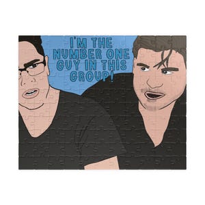 May include: A jigsaw puzzle featuring a cartoon illustration of two men. One man wears glasses and the other has dark hair. The text on the puzzle reads, "I'M THE NUMBER ONE GUY IN THIS GROUP!"