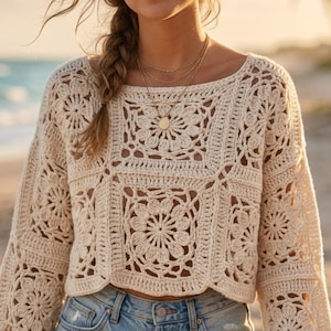 Pode incluir: Top de crochê creme com um padrão floral quadrado. A parte superior de manga comprida apresenta um decote redondo e é feita de um material macio e de tecido aberto. O design de crochê inclui motivos florais em toda a peça, criando uma estética boêmia.