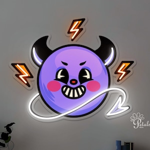 May include: A neon light fixture shaped like a cartoon devil with a purple face, black horns, and a white tail. Orange lightning bolts surround the devil. The fixture is mounted on a light gray wall above a wooden cabinet.