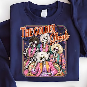 A blue sweatshirt with a graphic design featuring four stylized female skeletons dressed in colorful outfits, with the text "The Golden Ghouls" above them.