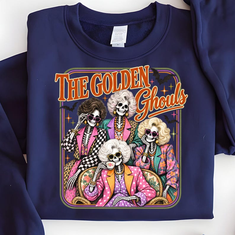 A blue sweatshirt with a graphic design featuring four stylized female skeletons dressed in colorful outfits, with the text "The Golden Ghouls" above them.