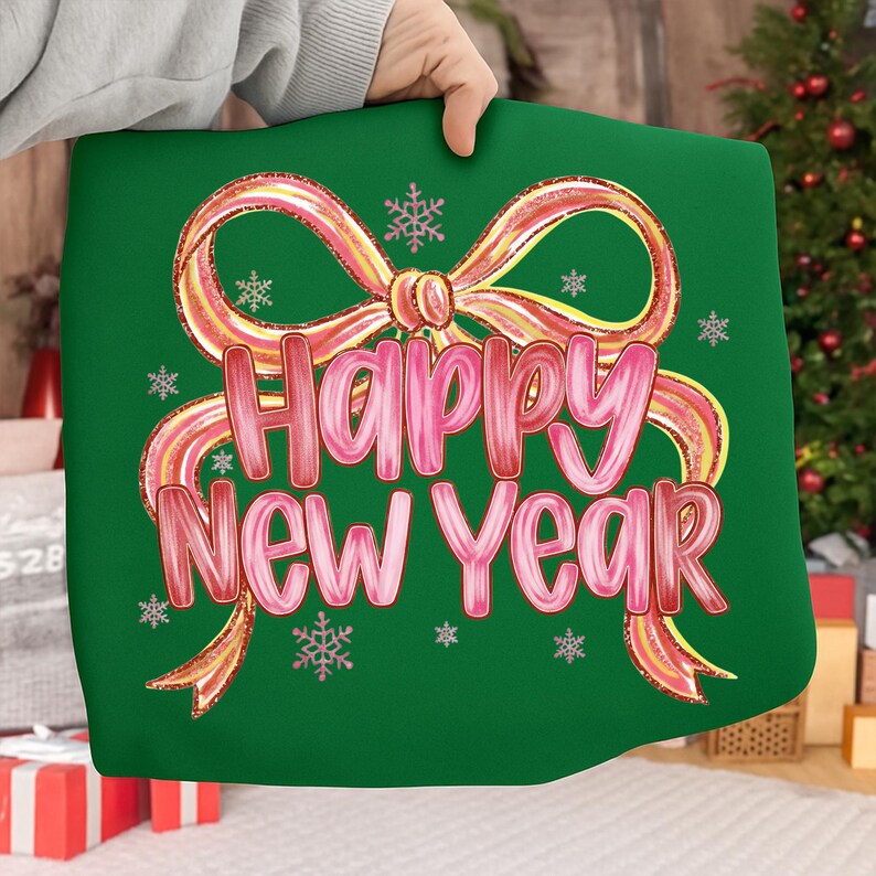 May include: A green pillow with a pink and gold bow design and the words "Happy New Year" in pink script. The pillow also features small snowflake accents, perfect for holiday decor.
