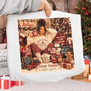 Op de afbeelding: Een wit sweatshirt met een grafische print van een persoon die voor een kerstboom zit. De print bevat de teksten "Christmas Calories don't count", "Dear Santa, I CAN EXPLAIN", "jingle all the way" en "Dear Santa, define good..." samen met kerstgerelateerde items.