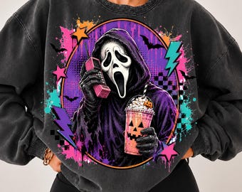 May include: A charcoal grey crewneck sweatshirt featuring a graphic of a hooded figure with a white ghost mask, holding a pink vintage telephone and a pumpkin-faced iced coffee cup, surrounded by neon pink, orange, and teal paint splatters.