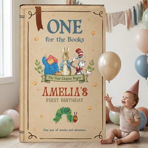 May include: A large, rectangular, tan-colored sign designed to look like a storybook cover. It features the text 'ONE for the Books', 'AMELIA'S FIRST BIRTHDAY', and 'The First Chapter Begins'. Illustrations include Paddington Bear, Peter Rabbit, the Cat in the Hat, and the Very Hungry Caterpillar.