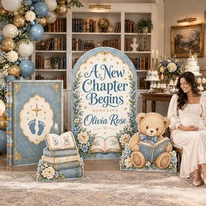 May include: A baby shower display featuring a large arched sign with the text A New Chapter Begins Honoring Olivia Rose, a tall book-shaped cutout, a stack of books, and a teddy bear cutout reading a book, all decorated with blue and white flowers.