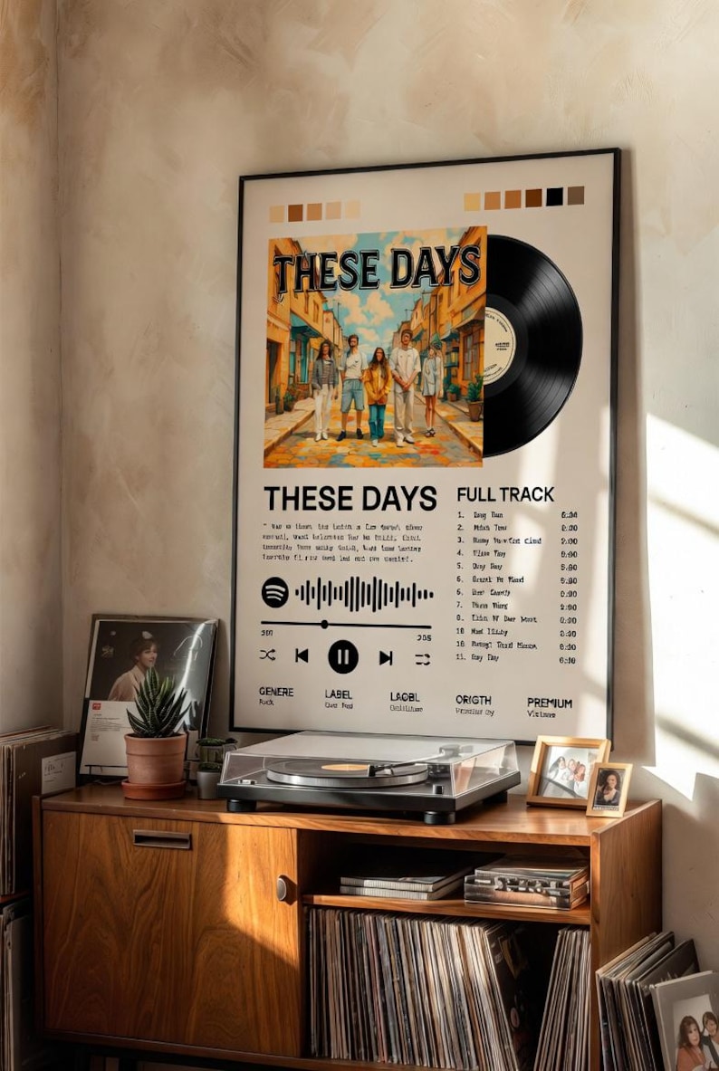May include: A framed wall poster featuring a vinyl record graphic, the title These Days, a central illustration of five people walking down a street, a Spotify code, and a tracklist. The poster includes color swatches at the top and text details.