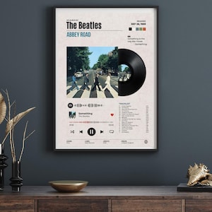 May include: A framed poster featuring The Beatles Abbey Road album artwork, a black vinyl record graphic, a tracklist, and a digital music player interface. The design includes the release date, song lyrics, and a Spotify-style playback bar.