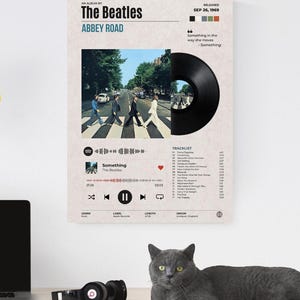 May include: A rectangular wall poster featuring The Beatles Abbey Road album artwork. It includes the iconic crosswalk photo, a black vinyl record graphic, a digital music player interface, tracklist, and release date of September 26, 1969.