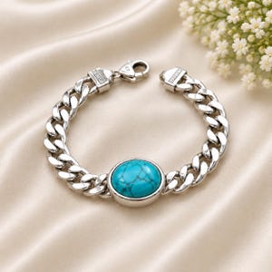 May include: A silver chain link bracelet featuring a central oval turquoise stone with dark veining. The bracelet is constructed with polished metal links and includes a secure lobster claw clasp mechanism for fastening around the wrist.