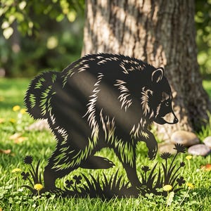 Könnte beinhalten: Eine schwarze Metallsilhouette eines Waschbären in Laufpose mit detaillierter Fellstruktur und buschigem Schwanz. Der Waschbär ist von ausgeschnittenen Formen aus Gras und kleinen Blumen umgeben, die ein dekoratives Gartenstecker-Design bilden.