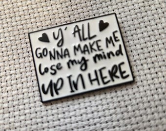 Peut inclure: Une épingle en émail blanc avec une bordure noire et l'inscription "y'all gonna make me lose my mind up in here" en lettres noires. Deux coeurs noirs sont sur les coins supérieurs de l'épingle.