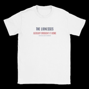 Puede incluir: Una camiseta blanca de manga corta con el texto THE LIONESSES en azul oscuro, ALREADY BROUGHT IT HOME en rojo, y EURO 2022 & 2025 CHAMPIONS en letras negras pequeñas centrado en la zona del pecho de la prenda.