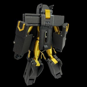 May include: A black and gold robot toy with articulated joints. The robot has a boxy design with gold accents on the arms, legs, and head. The toy is standing against a black background.